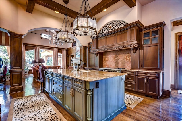 kitchen featuring dark hardwood / wood-style flooring, an island with sink, high vaulted ceiling, sink, and decorative light fixtures