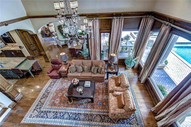 living room with hardwood / wood-style floors, a notable chandelier, and a towering ceiling