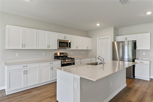 kitchen with white cabinetry, stainless steel appliances, sink, and an island with sink