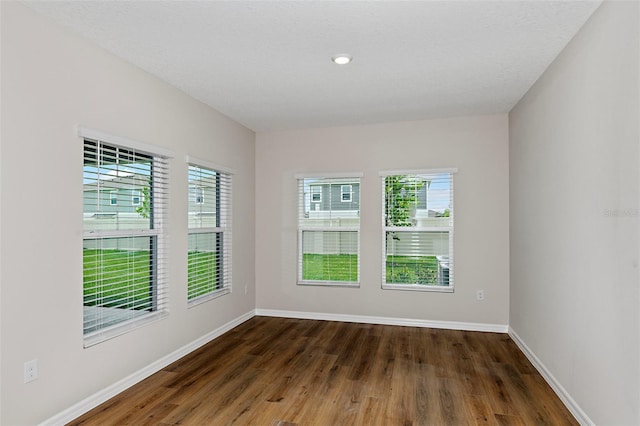 unfurnished room featuring dark wood-type flooring, a textured ceiling, and a wealth of natural light