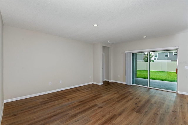 spare room with a textured ceiling and dark hardwood / wood-style floors