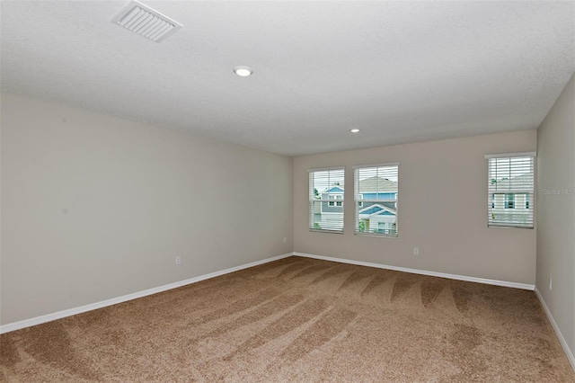 carpeted empty room with a textured ceiling