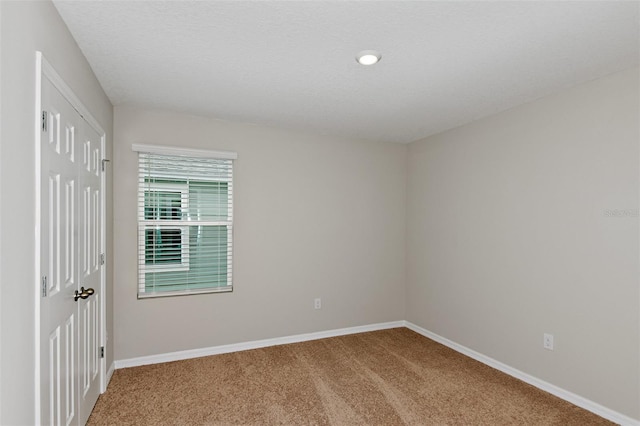 carpeted empty room featuring a textured ceiling