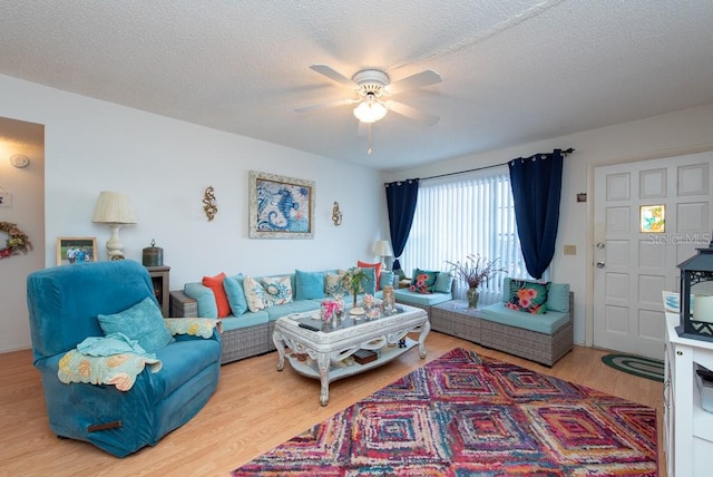 living room with ceiling fan, hardwood / wood-style flooring, and a textured ceiling