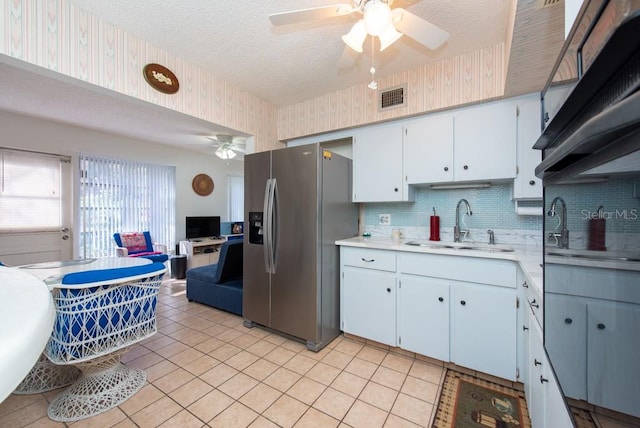 kitchen with decorative backsplash, white cabinets, ceiling fan, stainless steel refrigerator with ice dispenser, and sink