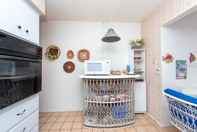 kitchen with oven, light tile patterned floors, white cabinetry, a textured ceiling, and wood walls