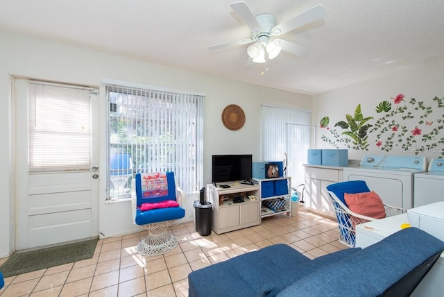 tiled living room with separate washer and dryer and ceiling fan