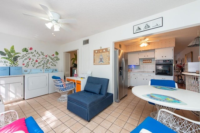 living room with ceiling fan, independent washer and dryer, a textured ceiling, and light tile patterned floors