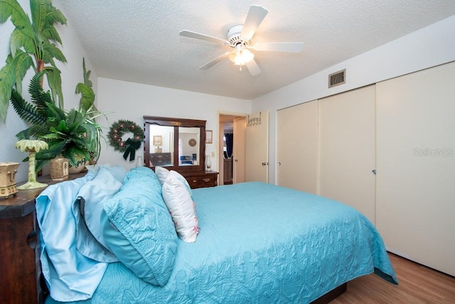 bedroom featuring a textured ceiling, hardwood / wood-style flooring, a closet, and ceiling fan