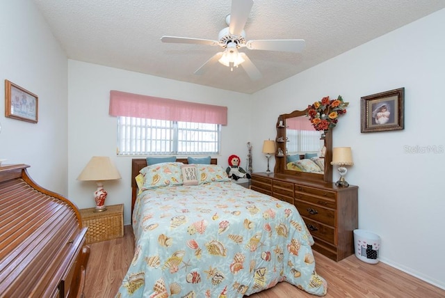 bedroom featuring a textured ceiling, light wood-type flooring, and ceiling fan