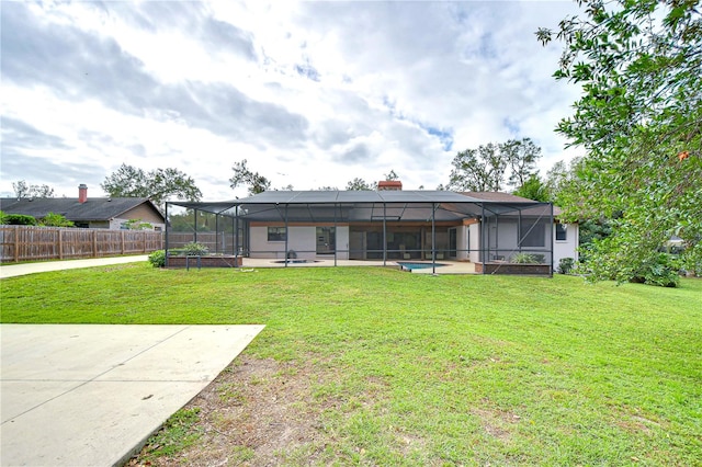 rear view of house with glass enclosure, a yard, and a patio