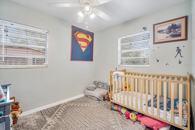 carpeted bedroom with ceiling fan and a crib