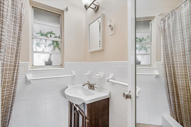 bathroom with curtained shower, vanity, and tile walls