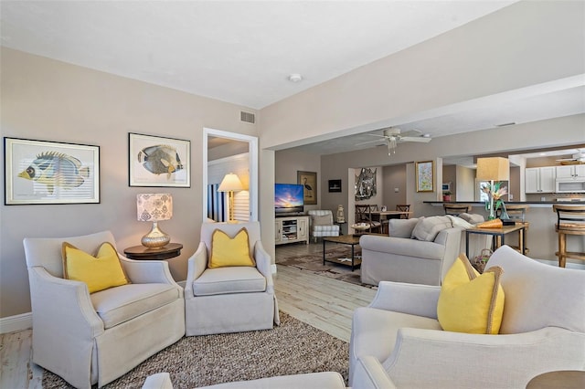 living room with ceiling fan and light hardwood / wood-style flooring