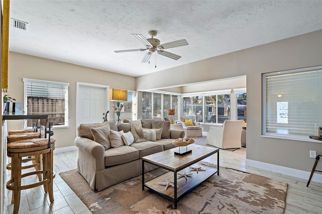 living room featuring a textured ceiling, ceiling fan, and light hardwood / wood-style flooring