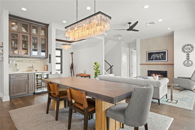 dining space featuring wine cooler, dark hardwood / wood-style flooring, a tile fireplace, and bar area