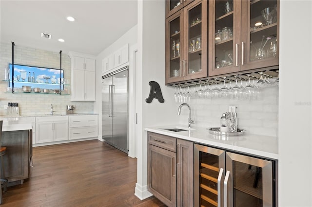 bar featuring tasteful backsplash, sink, white cabinetry, wine cooler, and built in fridge