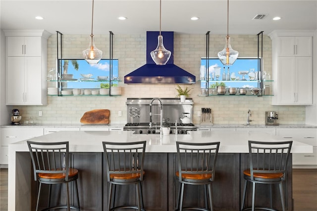 interior space featuring pendant lighting, white cabinetry, wall chimney range hood, and backsplash