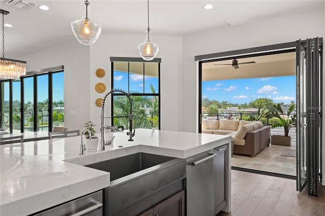 kitchen featuring ceiling fan, sink, light stone counters, pendant lighting, and light hardwood / wood-style floors