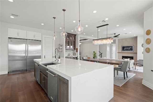 kitchen with a large fireplace, stainless steel appliances, a spacious island, pendant lighting, and white cabinets