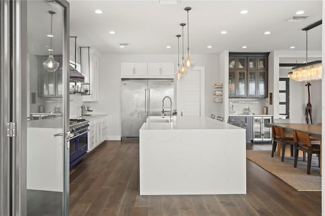 kitchen with white cabinetry, a center island with sink, beverage cooler, and decorative light fixtures