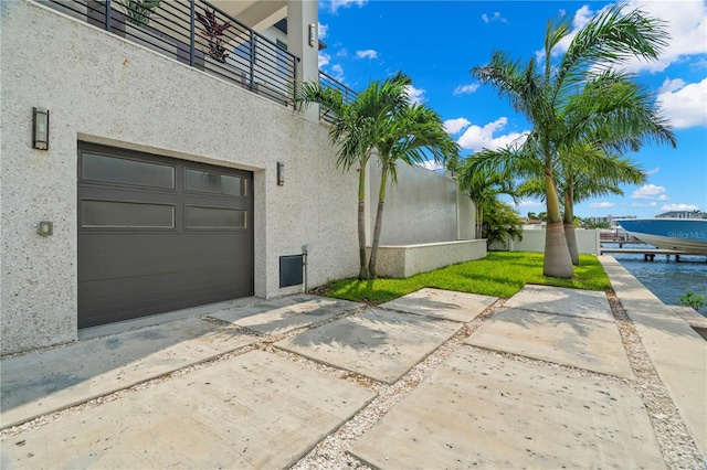 exterior space with a garage, a balcony, and a water view