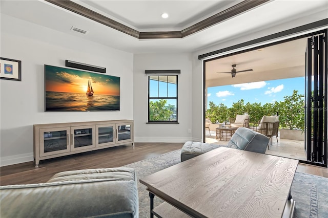 interior space with wood-type flooring, a tray ceiling, ceiling fan, and crown molding