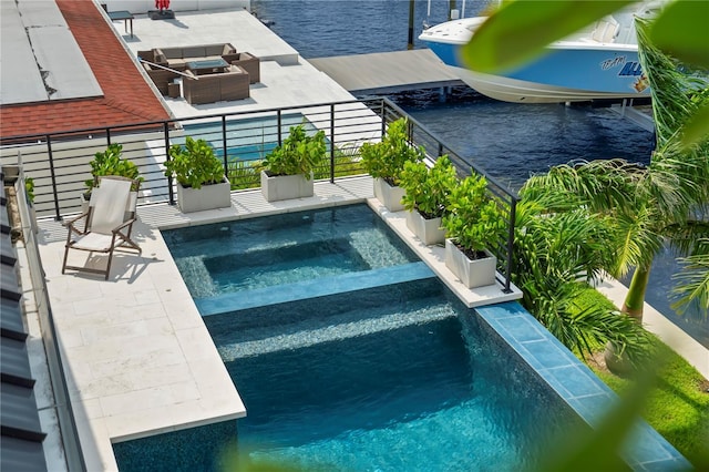 view of swimming pool with an in ground hot tub, a water view, and a patio area