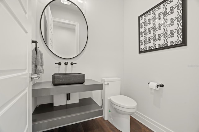 bathroom with hardwood / wood-style flooring, toilet, and sink