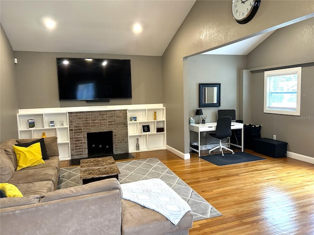 living room with hardwood / wood-style flooring, lofted ceiling, and a fireplace