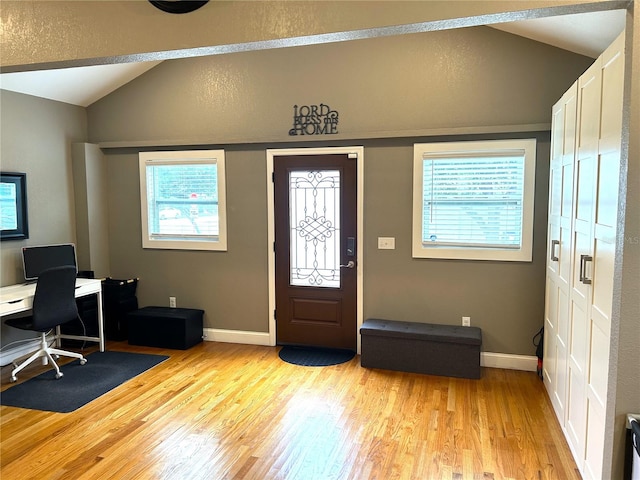 foyer entrance featuring light hardwood / wood-style floors, a wealth of natural light, and vaulted ceiling