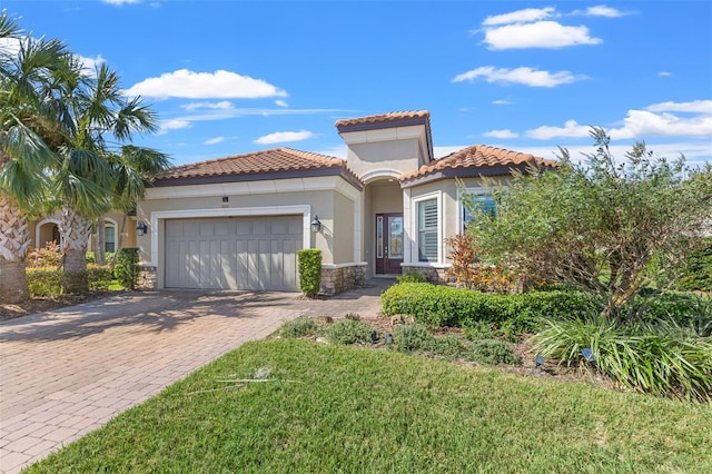 mediterranean / spanish house featuring decorative driveway, stone siding, an attached garage, and stucco siding