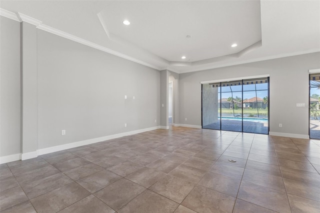 tiled empty room featuring ornamental molding and a raised ceiling