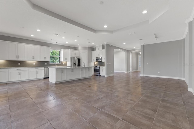 kitchen with tasteful backsplash, an island with sink, white cabinetry, stainless steel appliances, and crown molding