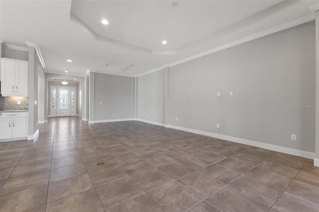 unfurnished living room with ornamental molding, a tray ceiling, and tile patterned floors