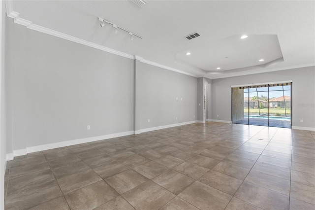 tiled empty room with a raised ceiling, ornamental molding, and track lighting