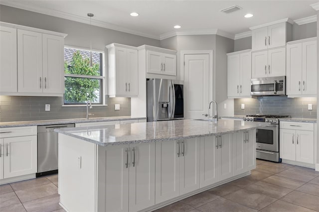 kitchen with white cabinetry, decorative light fixtures, stainless steel appliances, and a center island with sink