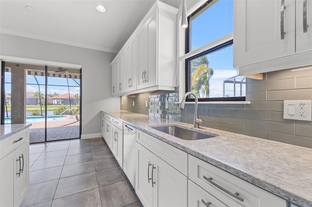 kitchen with light tile patterned floors, backsplash, white cabinetry, crown molding, and sink