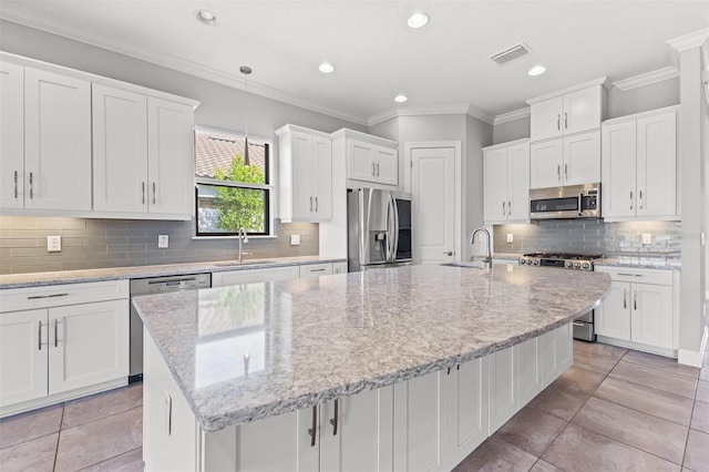 kitchen with white cabinetry, stainless steel appliances, and an island with sink