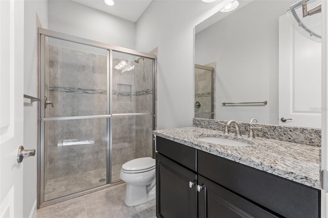 bathroom featuring vanity, toilet, tile patterned floors, and a shower with shower door