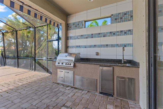 view of patio with sink, exterior kitchen, area for grilling, and glass enclosure