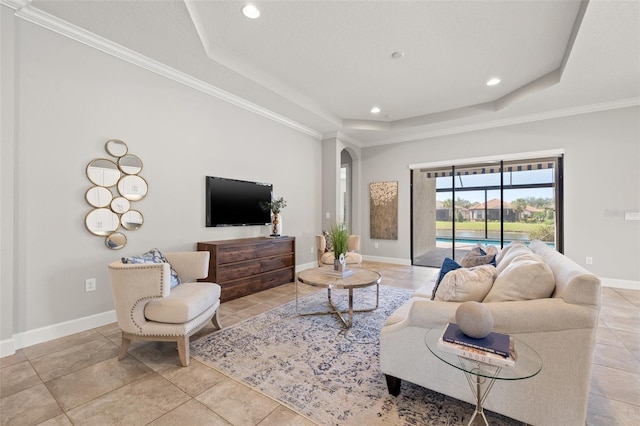 living room featuring arched walkways, recessed lighting, baseboards, ornamental molding, and a tray ceiling