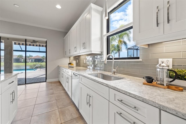 kitchen with dishwasher, light stone counters, a sink, and white cabinetry