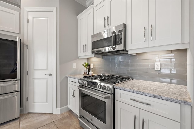 kitchen with light stone counters, light tile patterned floors, tasteful backsplash, appliances with stainless steel finishes, and white cabinets