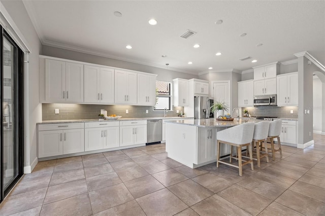 kitchen with appliances with stainless steel finishes, an island with sink, a breakfast bar area, and white cabinetry