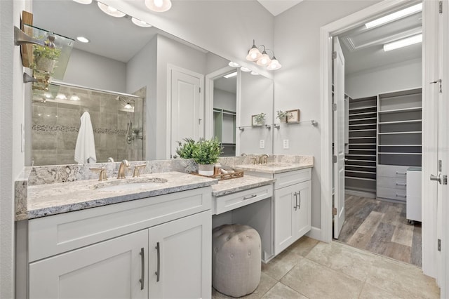 full bathroom featuring double vanity, a stall shower, tile patterned floors, a spacious closet, and a sink