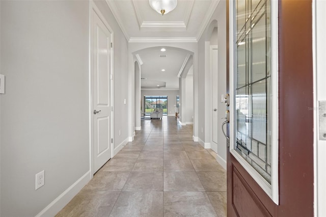 entryway featuring arched walkways, ornamental molding, light tile patterned flooring, and baseboards