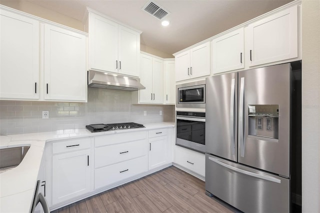 kitchen featuring tasteful backsplash, appliances with stainless steel finishes, light hardwood / wood-style flooring, and white cabinets