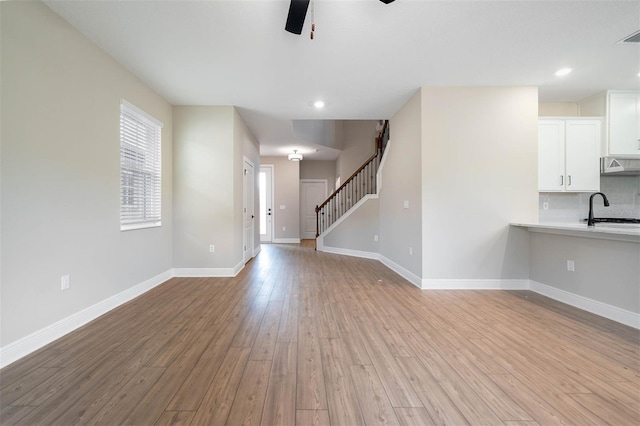 unfurnished living room with light hardwood / wood-style flooring, sink, and ceiling fan