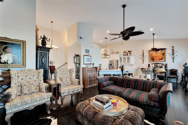 living room featuring vaulted ceiling, dark hardwood / wood-style flooring, and ceiling fan with notable chandelier